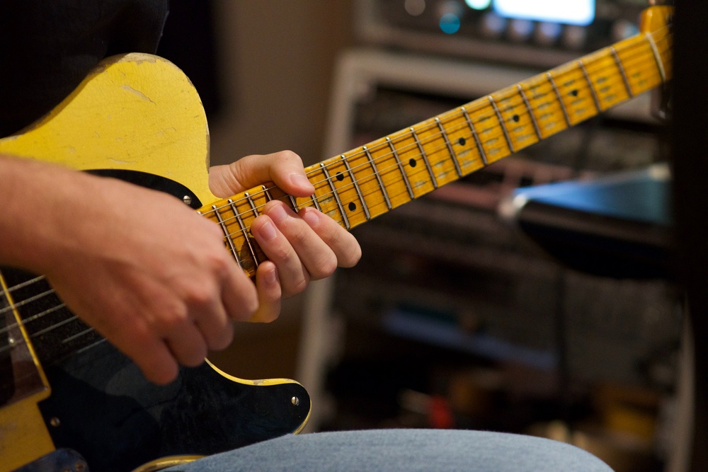 close-up on someone holding a yellow guitar and playing it