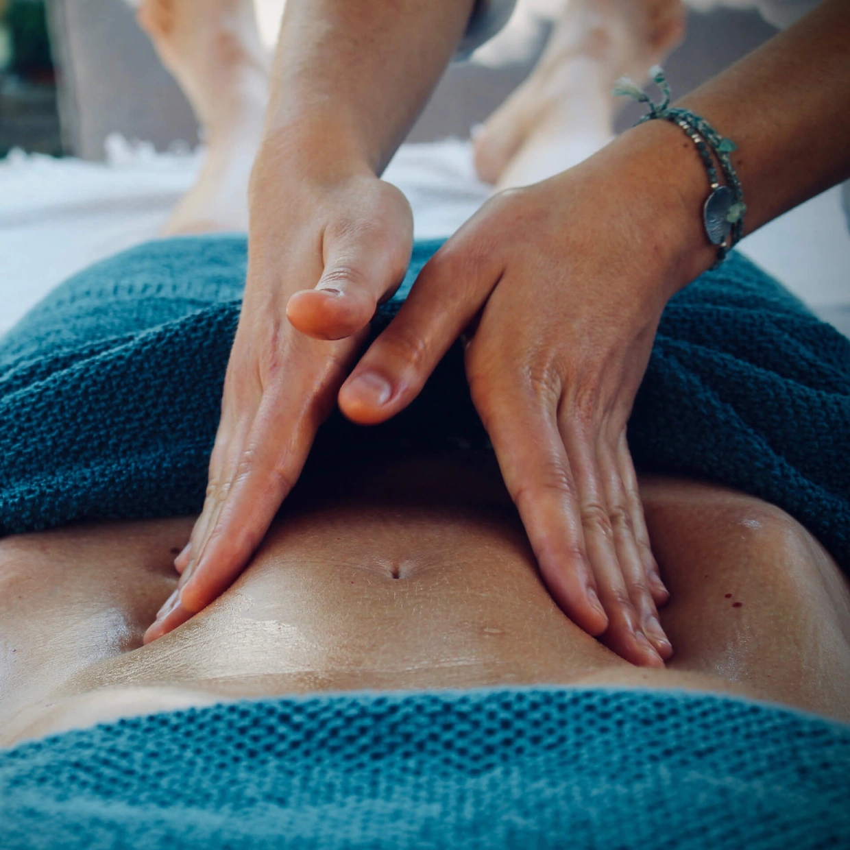 Deux mains qui massent le ventre d'une femme