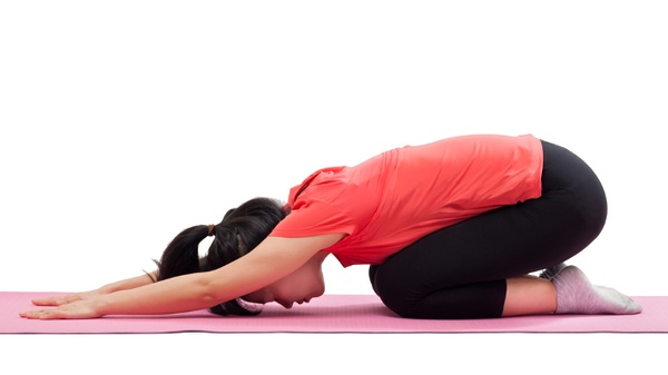 Flexible young female with curvy body exercising indoors, doing dhanurasana  or bow pose on yoga mat to strenghten back, open chest and shoulders,  improve digestion and stimulate reproductive organs Stock Photo