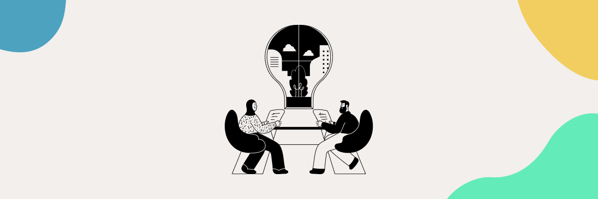 Two people sitting next to the giant bulb with a city inside of the bulb