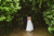 bride and groom walking through forest soil path 