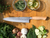 knife on wooden table surrounded by vegtables 