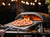 Ooni pizza oven with fire inside and a cooked pizza being taken out of the oven