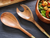 wooden serving spoons next to a metal salad bowl