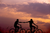 couple holding hands and riding a bike at sunset 