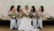 a bride and her bridesmaids sitting and holding bouquets 
