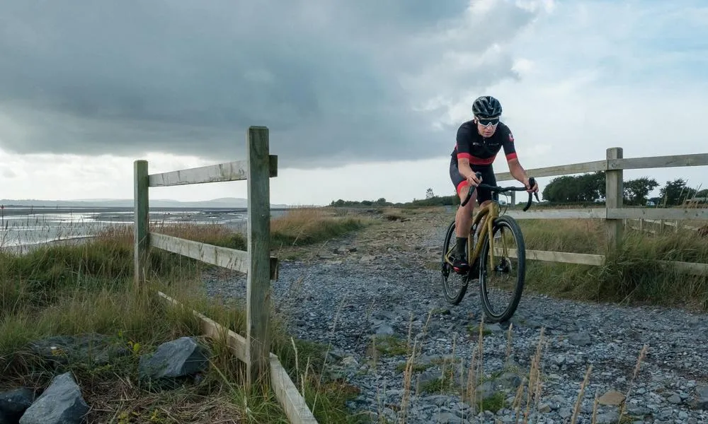 gravel rider on rough gravel track crossing a bridge on a moody day