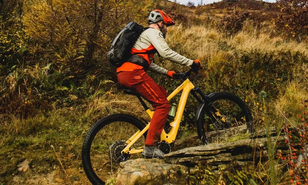 mtb rider cycling uphill on an e-bike wearing Endura trousers