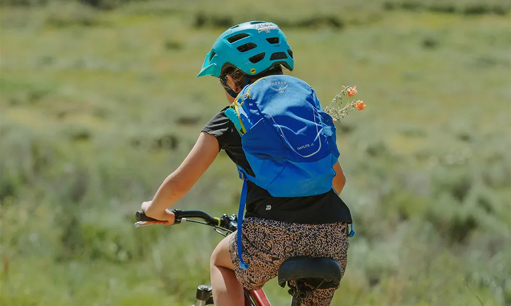 child riding a bike with an Osprey backpack