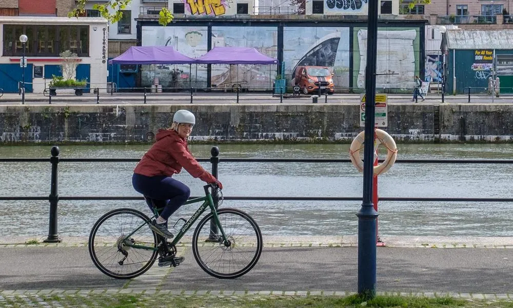 Cyclist riding past the river in Bristol