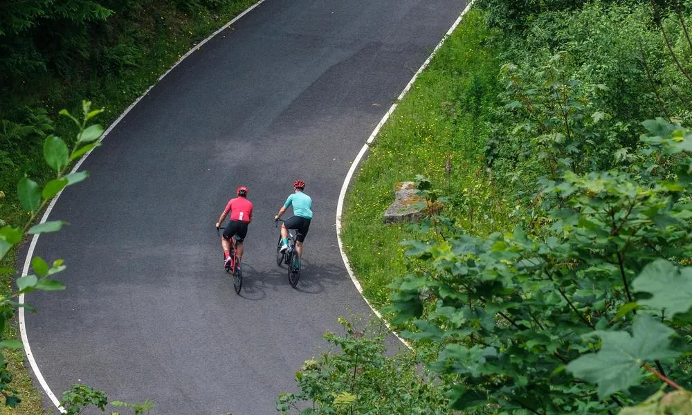 Two road cyclists climbing up a winding road shot form above