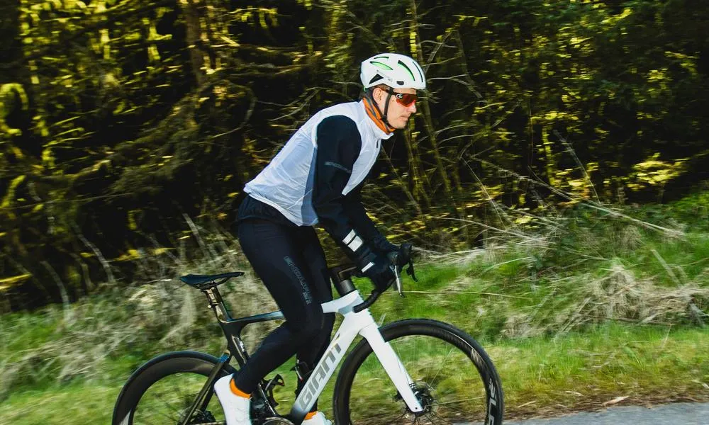 Road rider climbing a hill with a white vest on