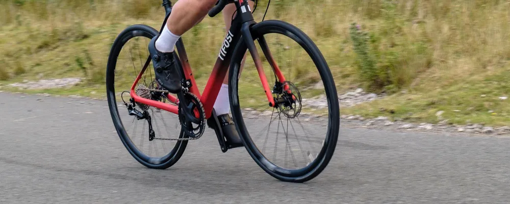 close up on the drivetrain and bottom bracket of a road bike riding uphill