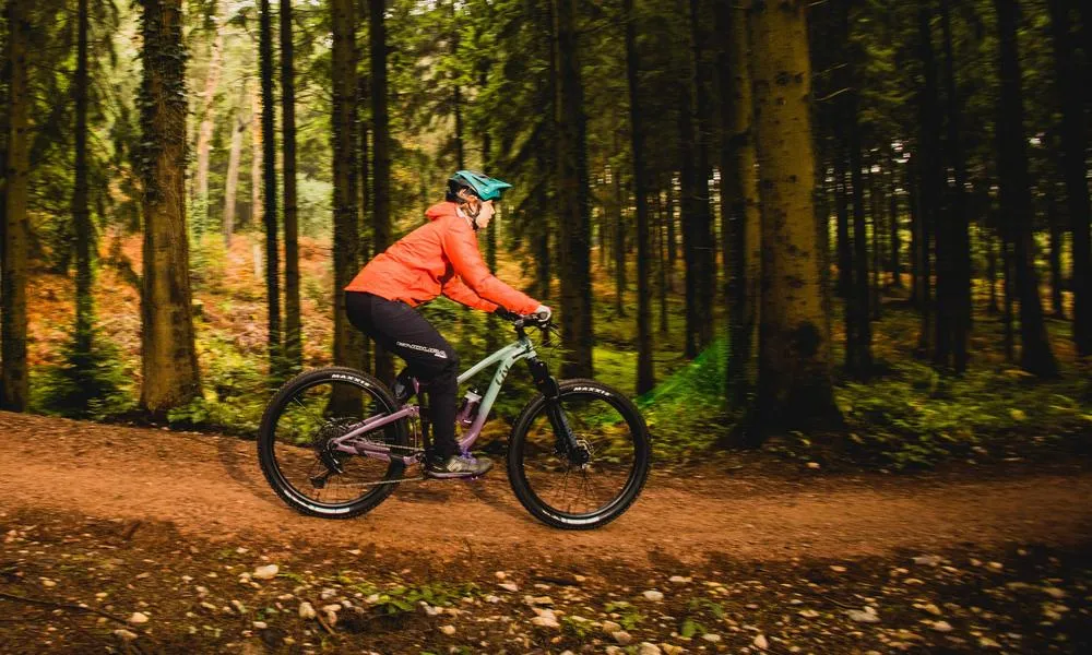 MTB rider descending through woods on a liv