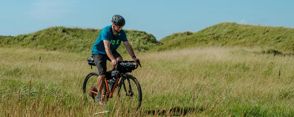 cyclist riding with frame and handlebar bags for bike packing