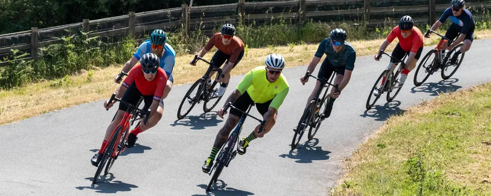 road cyclists riding in a bunch on a sunny day on an outdoor track