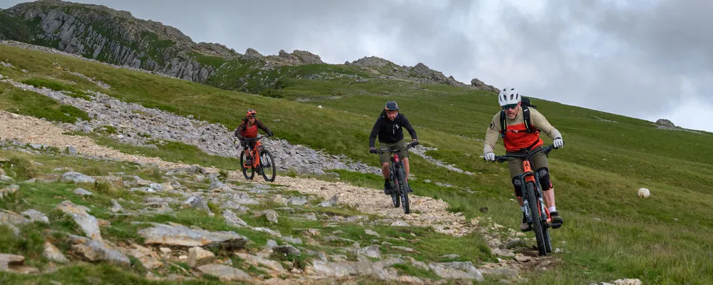 3 mountain bikers on mountain corner descending