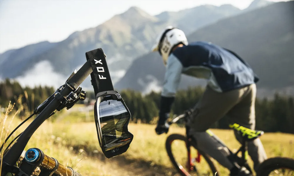 a pair of fox goggles hanging from handlebars