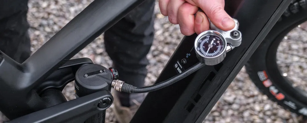 pumping up a rear shock on a mountain bike with a shock pump