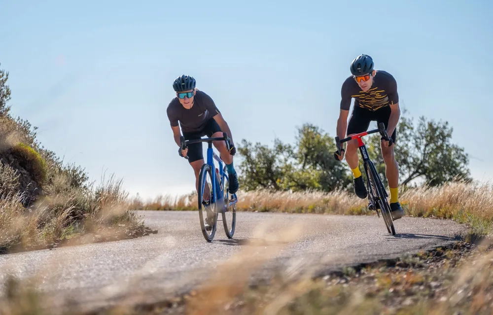 two road cyclist riding round a corner on a dry summer day