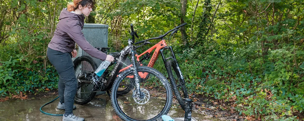 woman cleaning Specialized electric mountain bike with Peatys bike cleaner