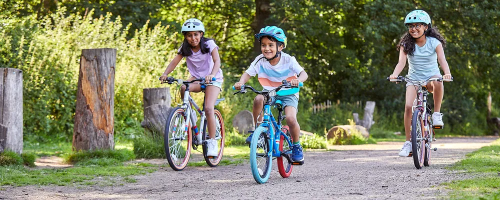 two girls and a younger boy riding kids bikes on a summer day