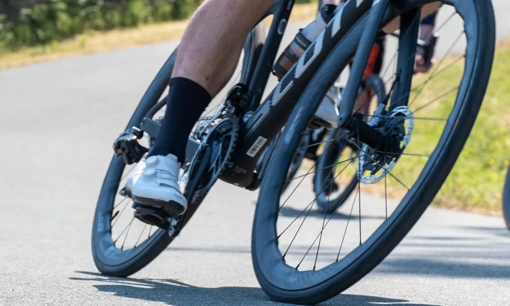 close up of a road bike being ridden showing wheels tyres and shoes