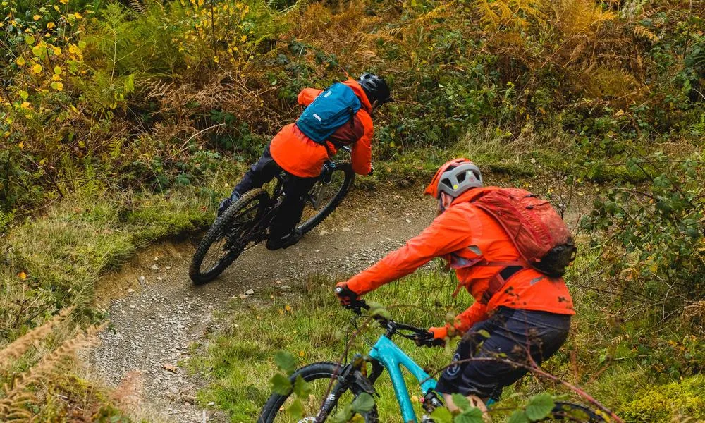 mountain bike bike riders wearing a camelbak ride down a trail