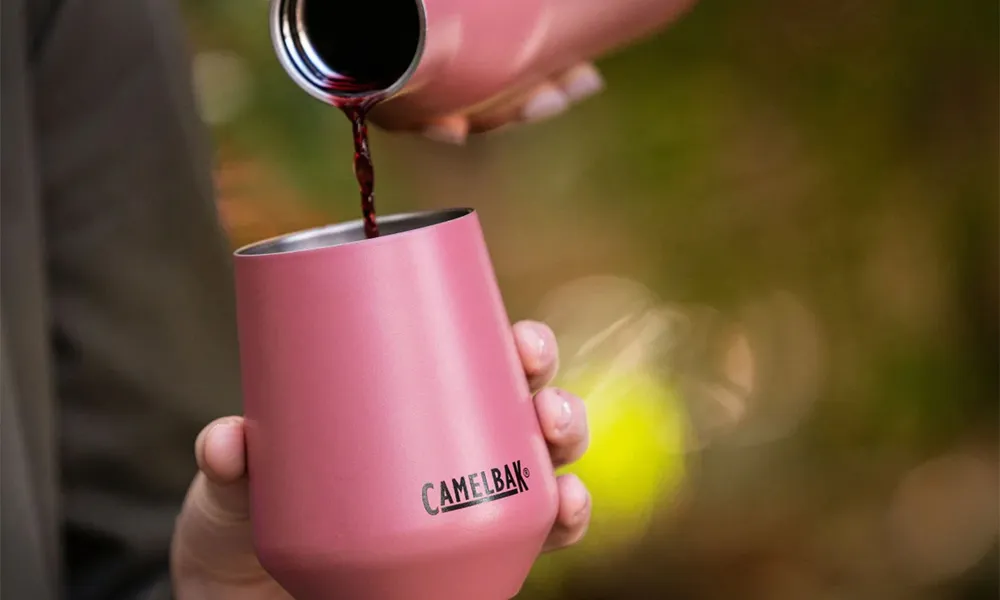 a red drink is poured into a pink travel mug