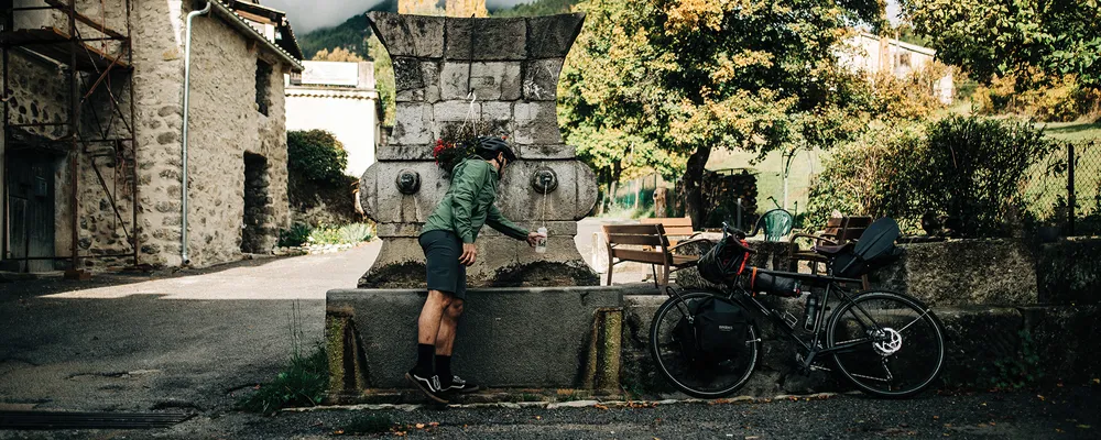 a water bottle is filled up while a touring bike rests nearby