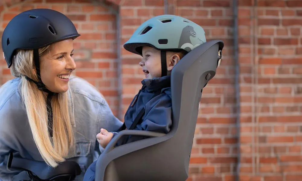 child in a bike child seat talking to adult