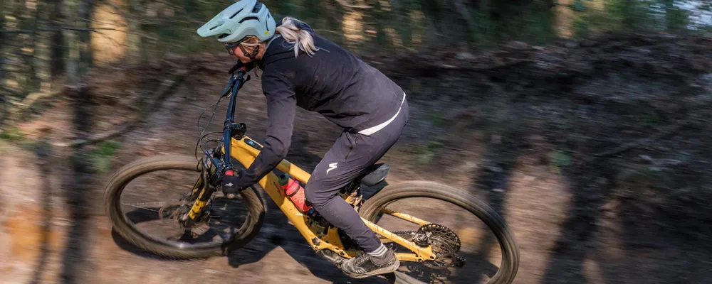 woman riding an electric mountain bike on traisl int the woods