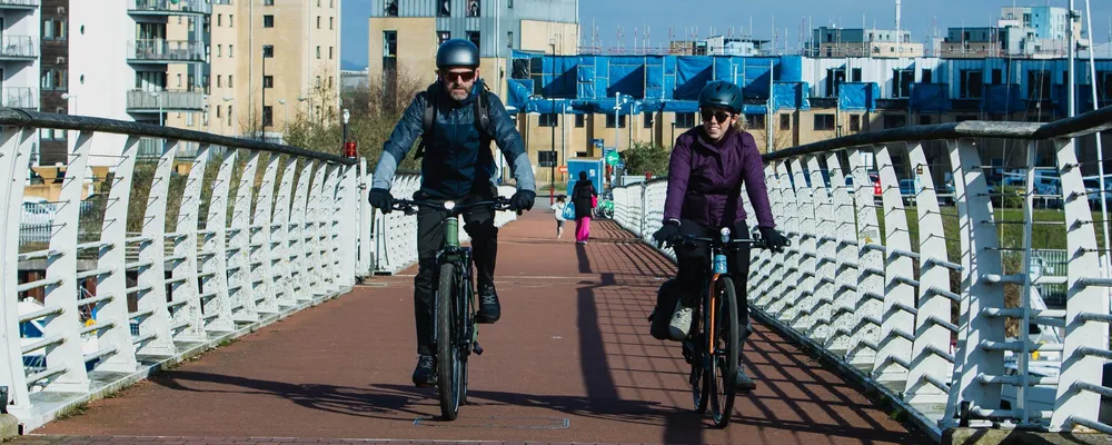 two cyclists riding urban bikes over a bridge