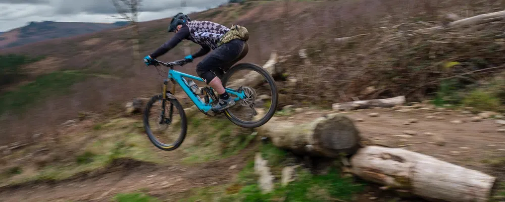 a mountain biker drops off a log at speed