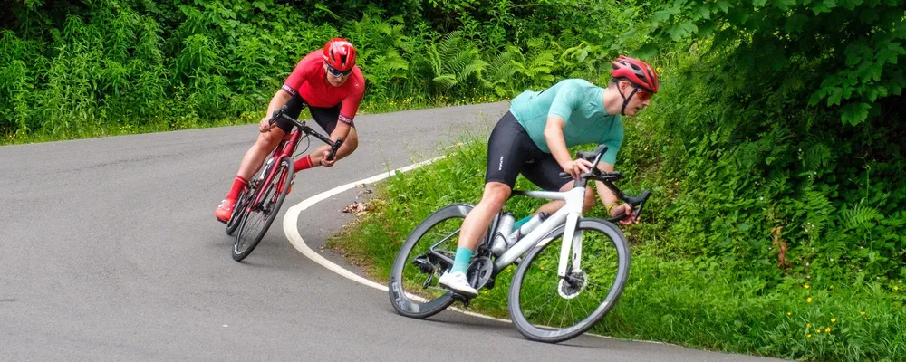 two road cyclist riding around a corner on a warm summer day