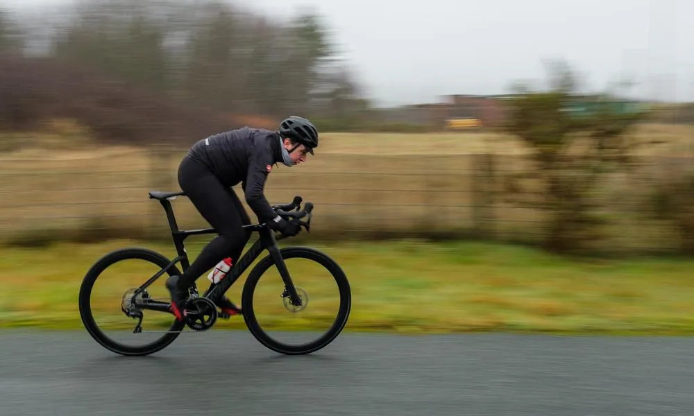 road cyclist riding fast on wet roads with Castelli rain gear