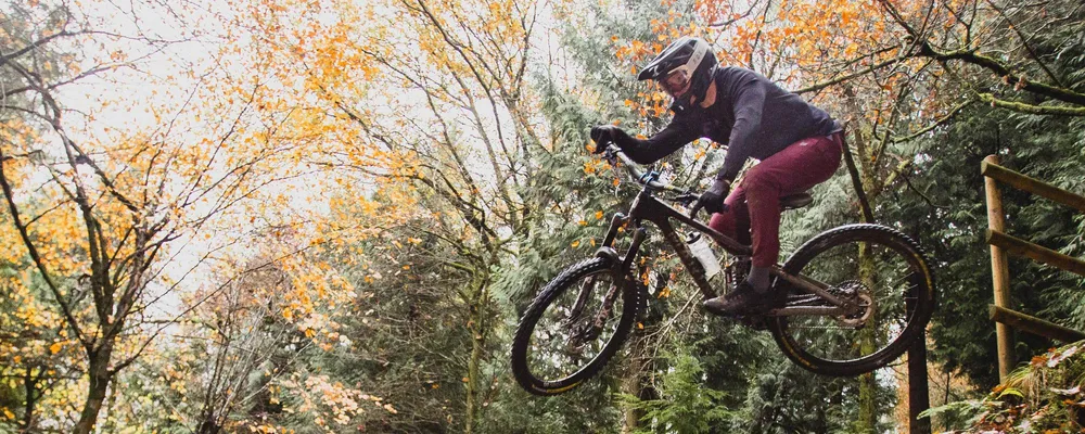 mountain biker flying off a drop in a full face helmet