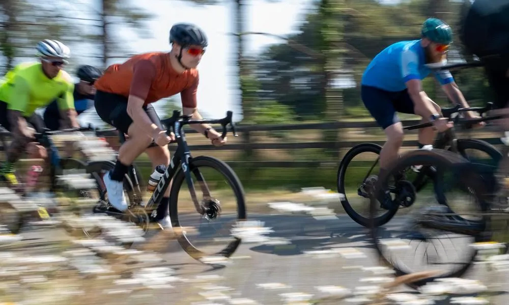 road cyclists riding fast past flowers