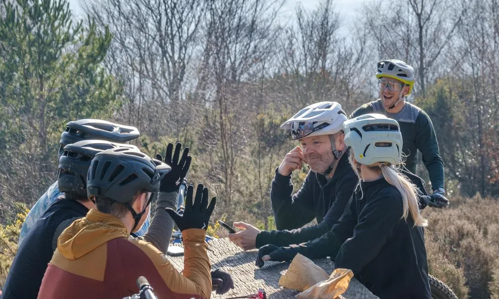 group of mountain bikers chatting in bike helmets