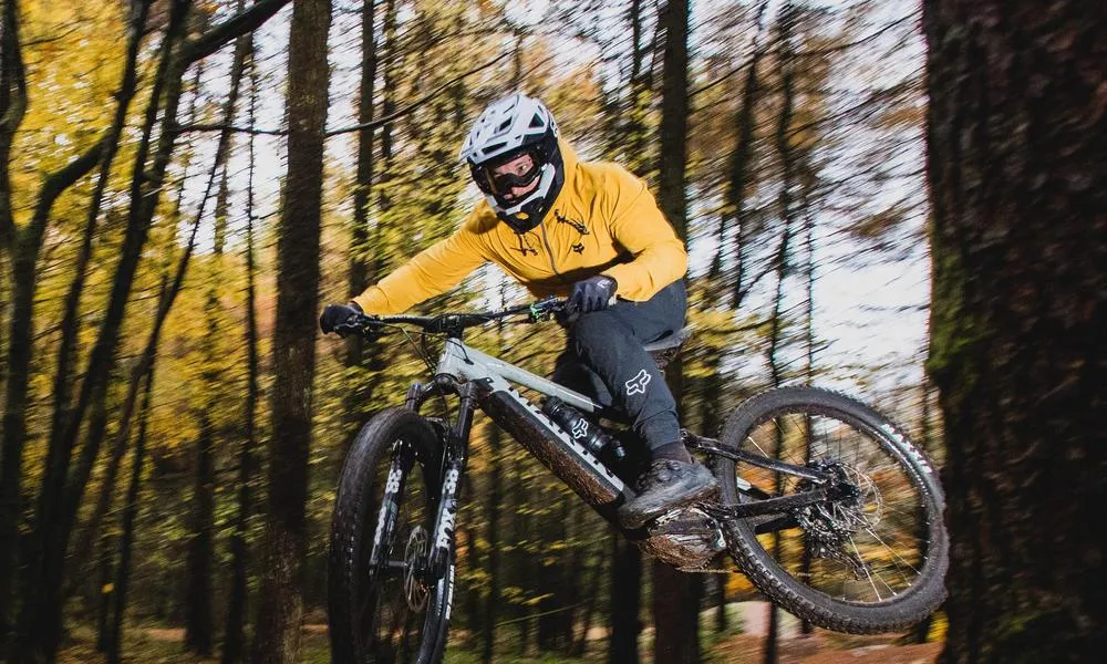 mountain biker jumping an ebike wearing goggles and full face helmet