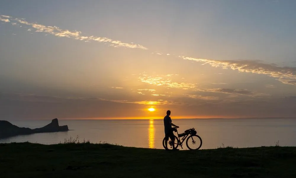 Sunset with bike packer silhouette of rider and gravel bike 