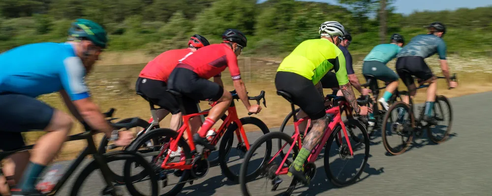 road cyclists riding in a group on a sunny day with different coloured clothing