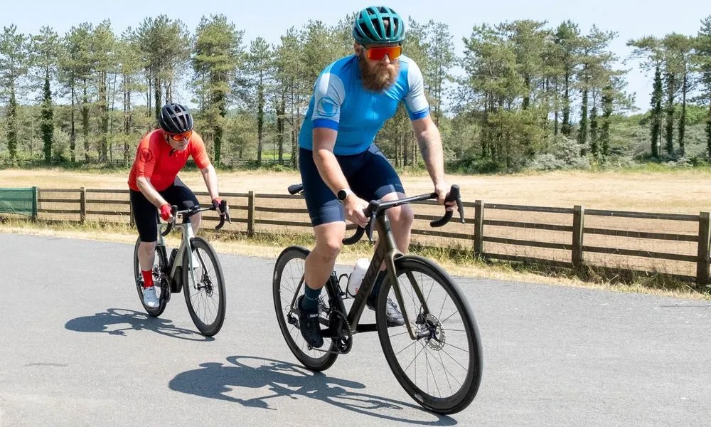 two road cyclists out of the saddle in the sun