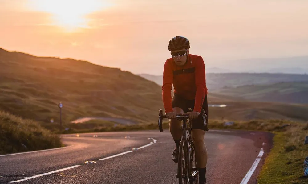 road cyclist climbing road in Welsh hills at sunset