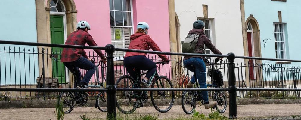 three cyclists riding past coloured houses in Bristol UK