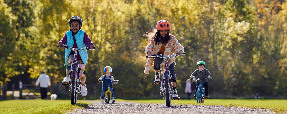 two girls riding 20"wheel bikes on an autumn day in the park