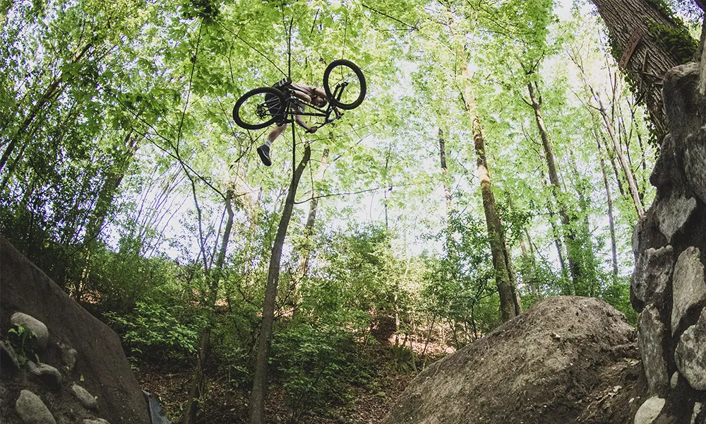 dirt jumps being ridden on a jump bike the rider is doing a one footed down table