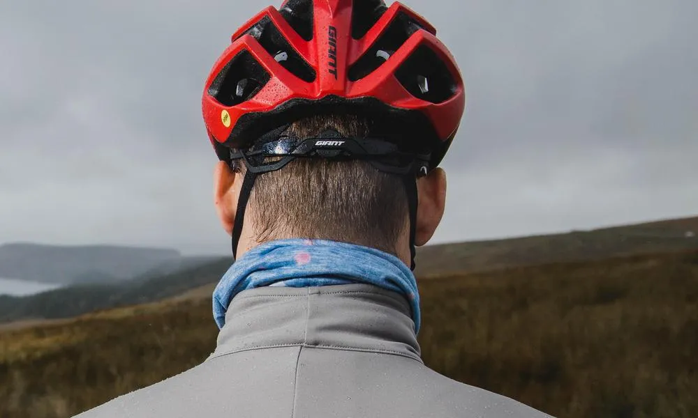 Road rider with a neck warmer facing away wearing a giant helmet