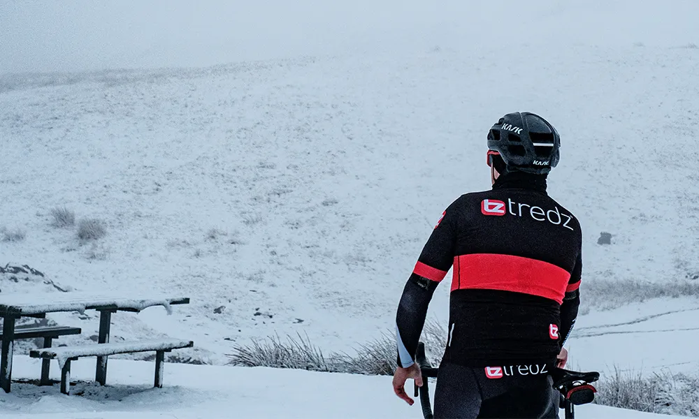 Road rider standing looking at the snow