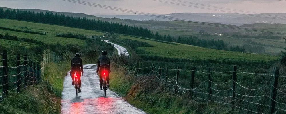 cyclists riding with rear bike lights at dusk on country lanes